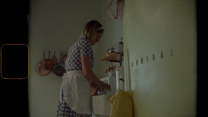 Female standing in front of sink in kitchen uses a sponge to thoroughly scrub a glass on the inside and outside