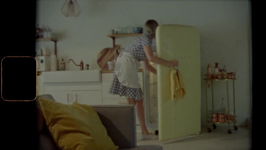 Vintage footage of a time lapse of a woman opening her fridge and getting something out
