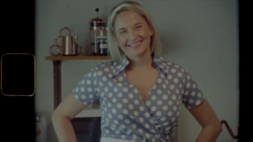 Blonde woman with a spotted dress poses for the camera in the kitchen