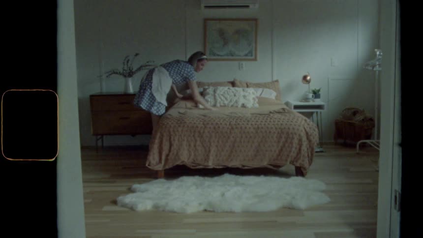 A woman makes the bed in a bedroom