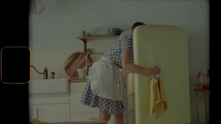 A woman walks in her kitchen to the fridge for something