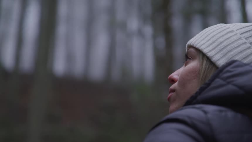 A woman is wearing a hat in the woods