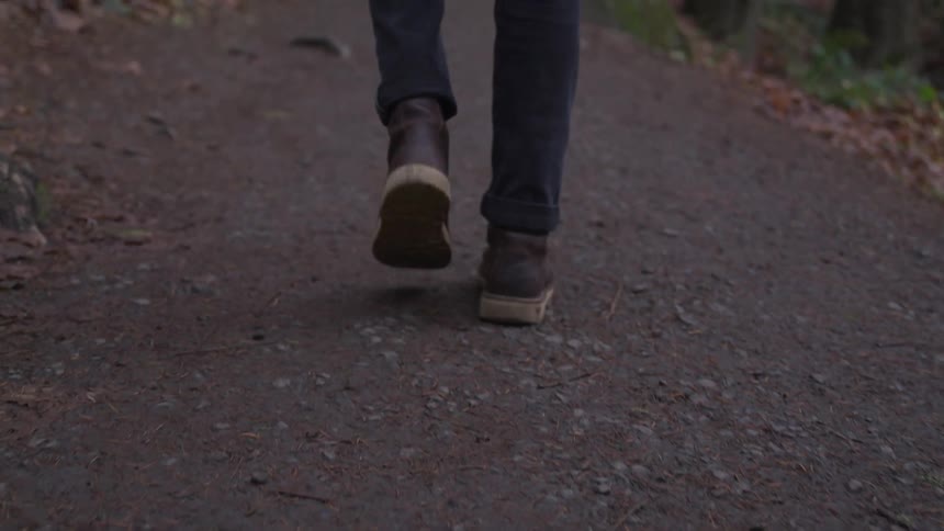 A person wearing sneakers walks along a paved outdoor path