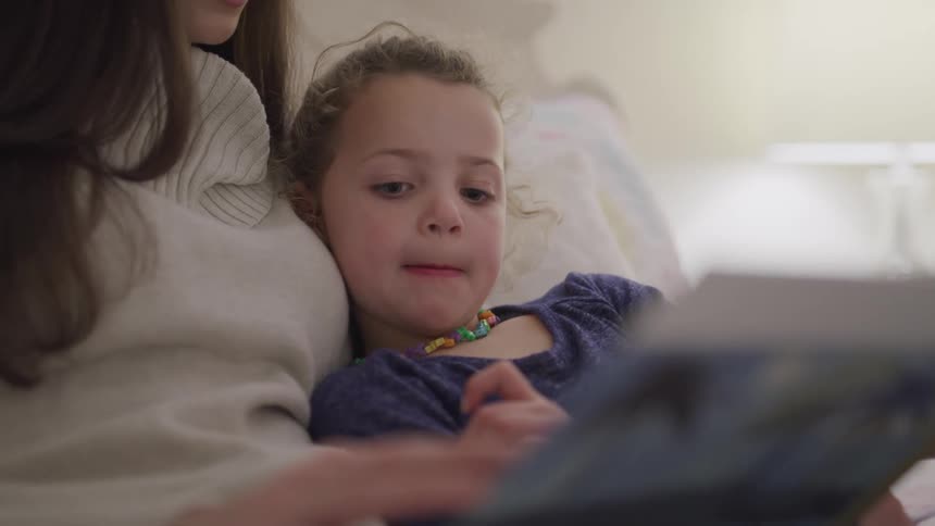 A mother reading a book to her small daughter
