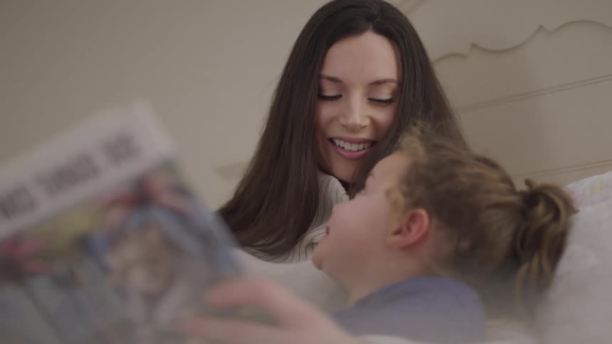 Daughter holding storybook exchanges smiles with her mother