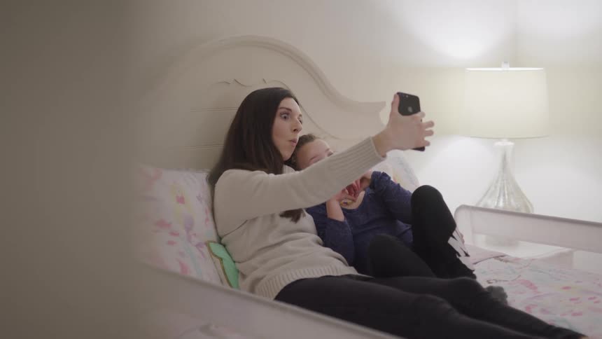 A teenage girl takes a selfie with her younger brother