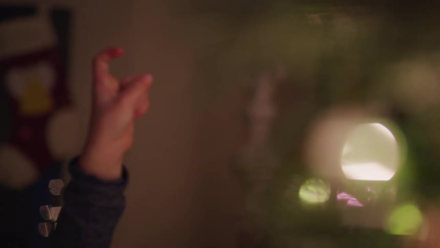 Small boy points finger up next to a christmas tree at home