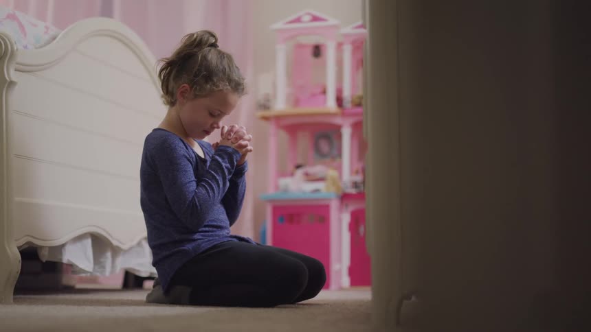 Young girl praying on the floor in her bedroom