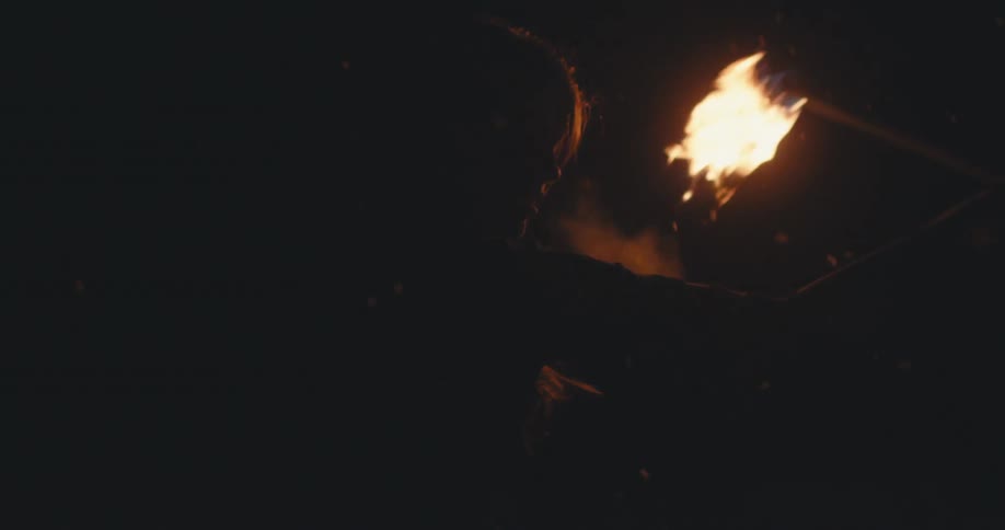 A fire dancer spins fire in the snow at night