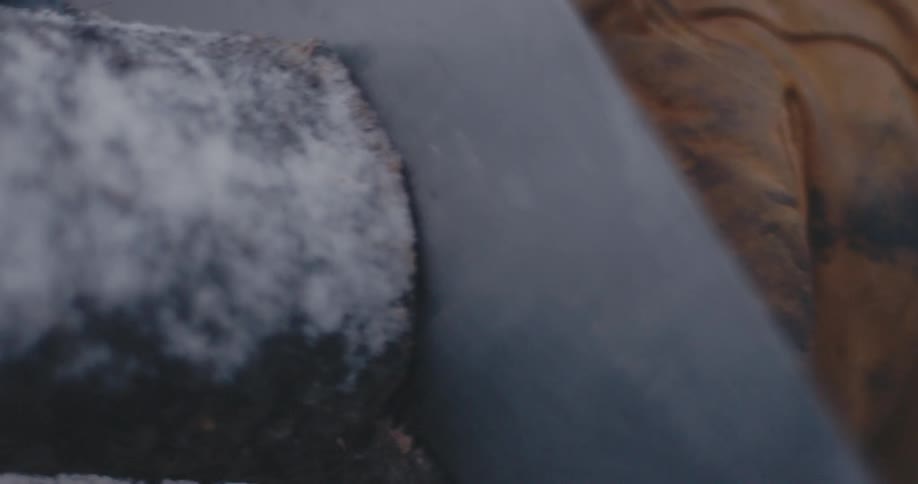 Close up of a gloved hand holding a branch while cutting it with a saw in the snow