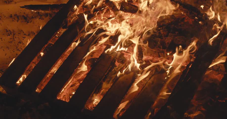 Flames burn vigorously as they consume a wooden pallet in a bonfire