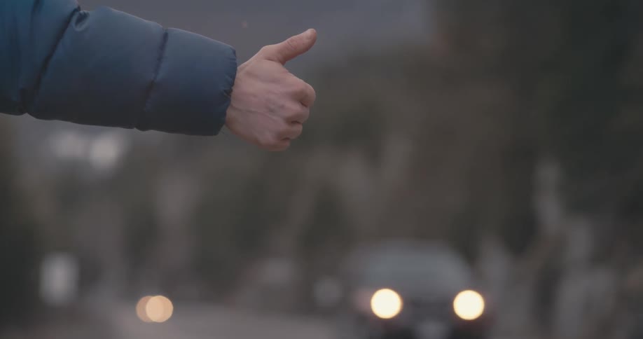 A hitchhiker holds his thumb up for traffic