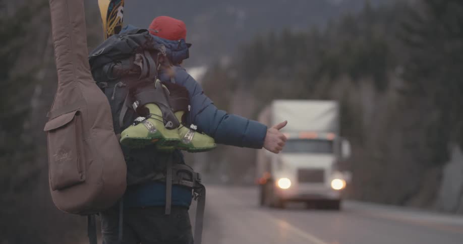 A male hitchhiker hitchhiking on the side of a road