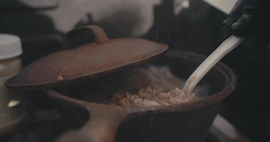 A person stirs a boiling pot of oatmeal