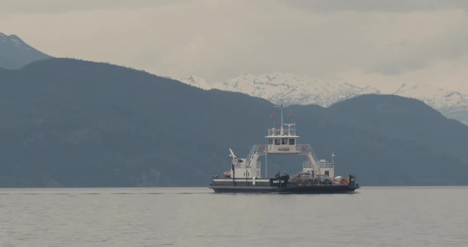 A ferry sailing through the water with mountains in the background