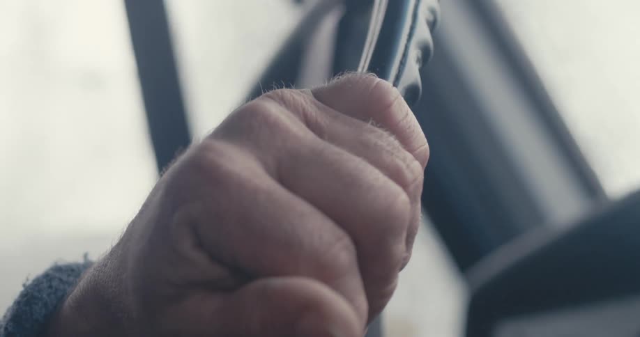 Old hands driving on a vintage steering wheel