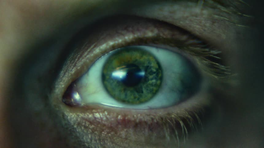 Close up of a green eye of a person looking at the camera