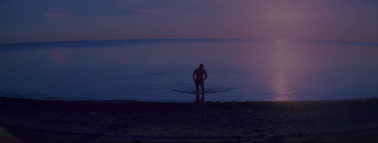 A man is walking towards the coast of a beach