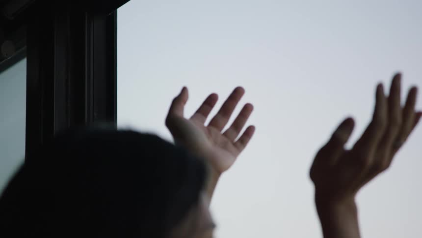 A woman stands on her balcony and claps