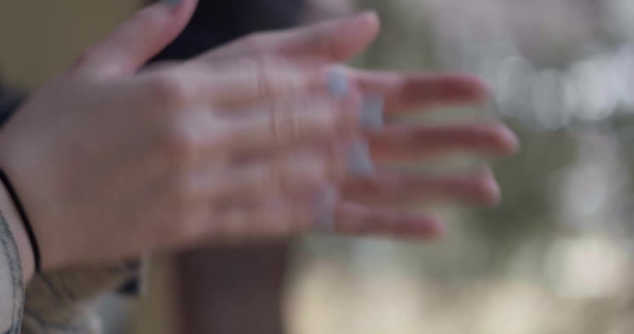 Two young white people clap their hands and move their arms in a frenzy while outdoors