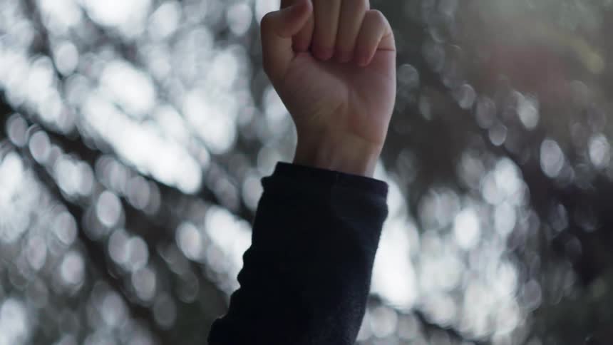 A white male puts his fist up in the air and shakes it