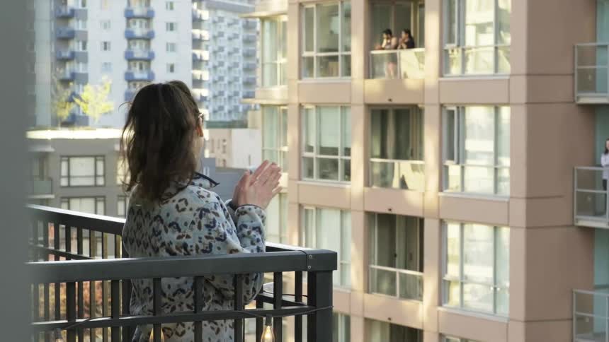 People stand on their apartment balcony and clap