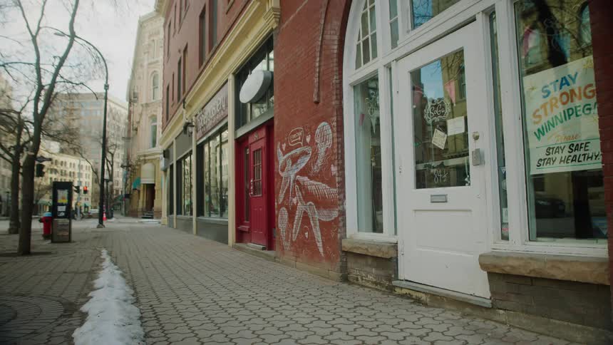 Storefronts along a city sidewalk stand empty of people