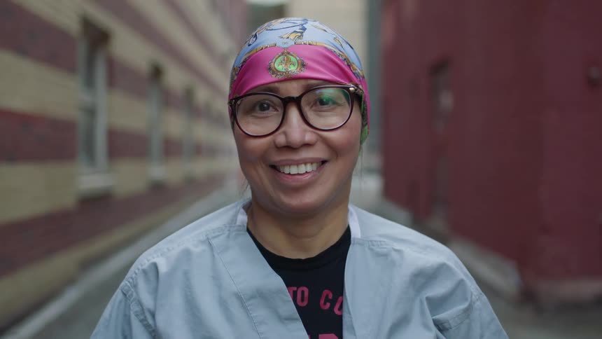 Asian woman stands and smiles happily in the alley
