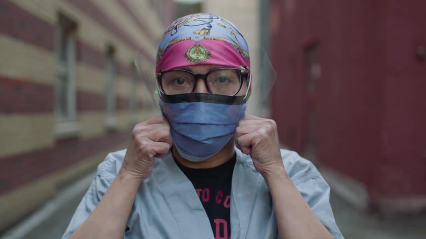 Female nurse wearing a face mask looks at the camera in the alley