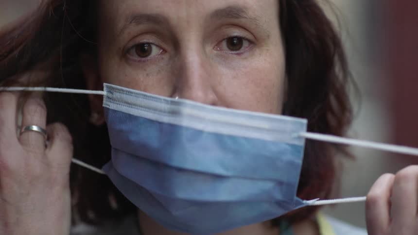 A medical worker removes a surgical mask