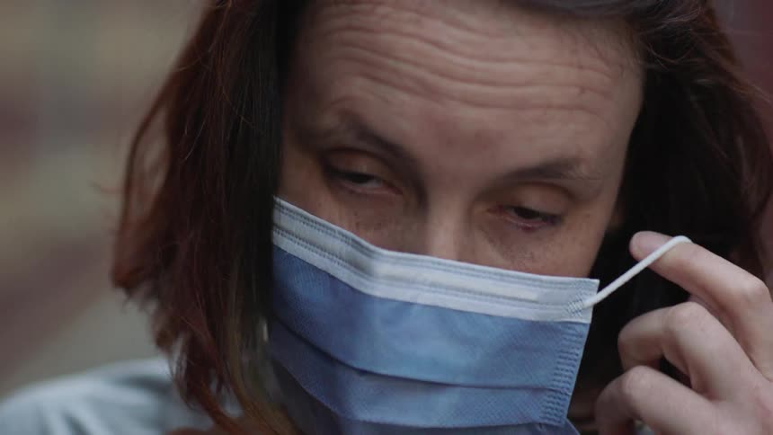A woman puts on a face mask