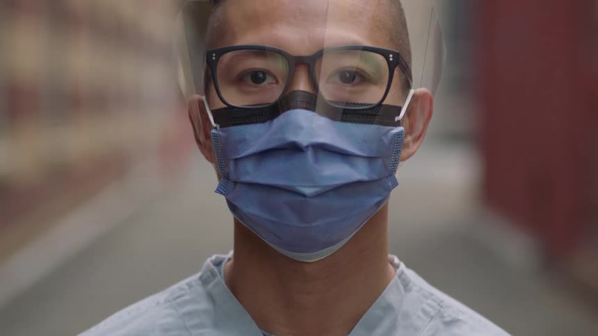 Male nurse wearing a face mask raises his head in the alley