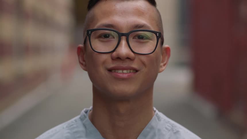 A nurse in black framed glasses looks up and smiles