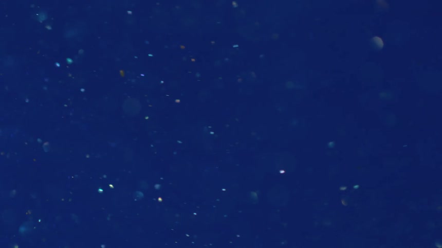 Particles reflecting light floating in the deep blue water