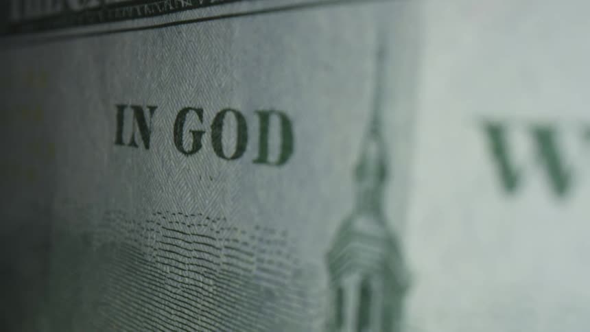 The motto printed across the top of a dollar bill is seen in great detail