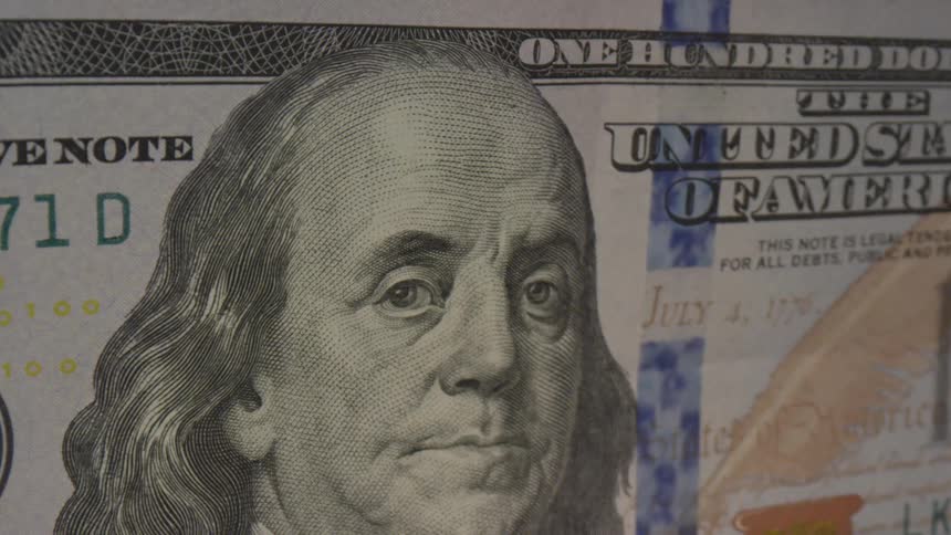 A blue security stripe runs to the right of benjamin franklins head on a one hundred dollar bill
