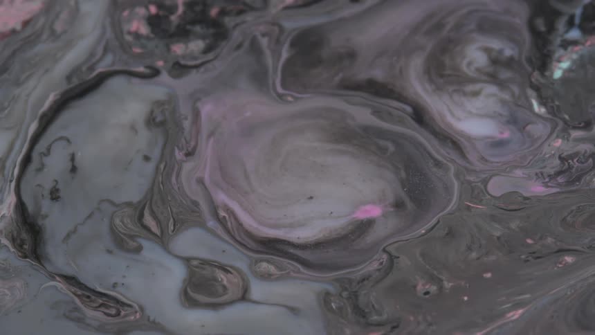 A viscous gray liquid is oozing and mixing as different shades of color blend together