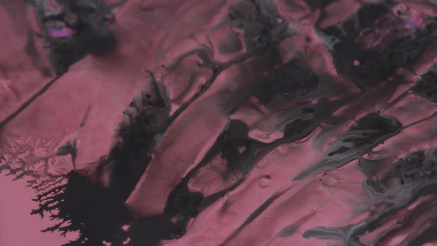 Pink and black paint flowing across surface