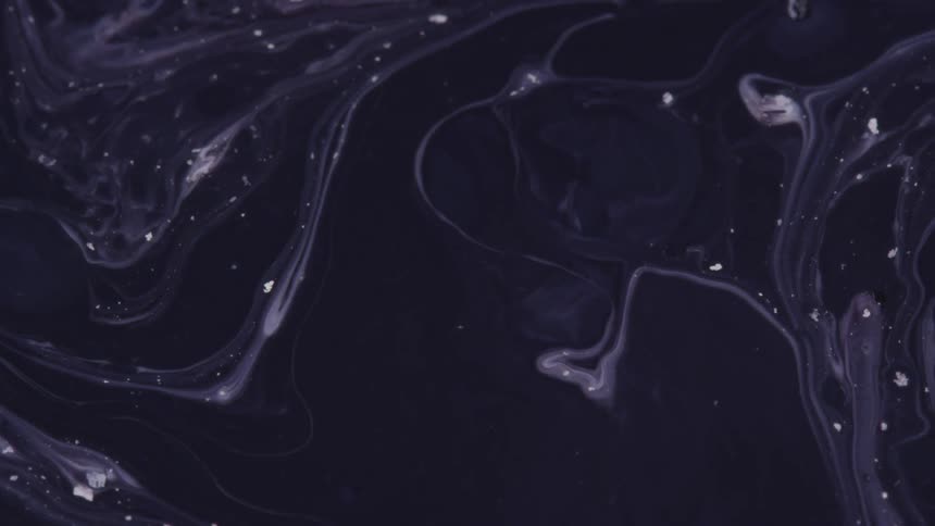 White streaks and flecks flow along surface of black liquid