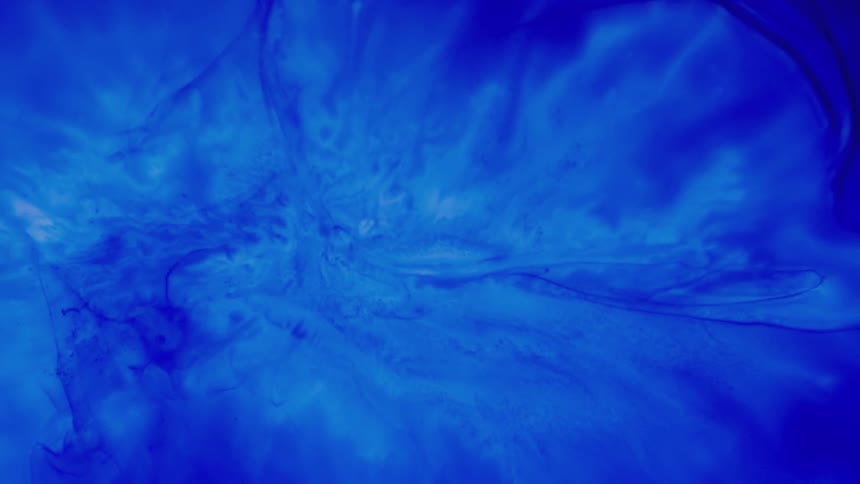 Blue liquid dye mixes with a white liquid dye and sinks to the center