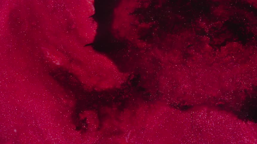 Bright gold sparks glitter among puffy reddish blue clouds separated by blackness