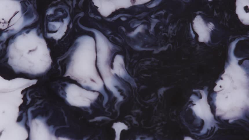 A mixture of black and white liquid flows slowly