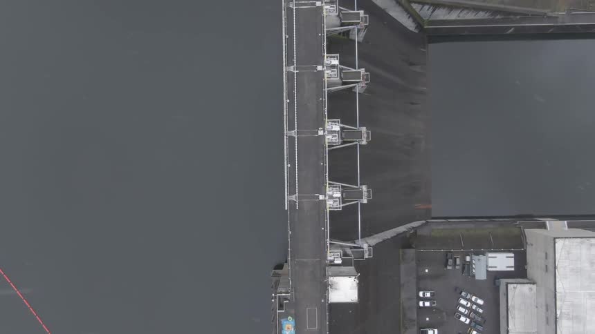 Aerial view of a person walking over a dam in a reservoir at winter