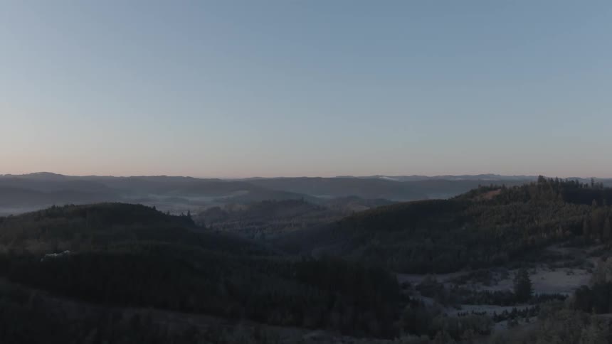 An aerial view of a landscape is displayed while the sun is setting