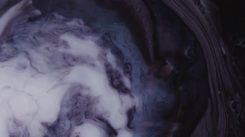 A white liquid flows into a darker liquid