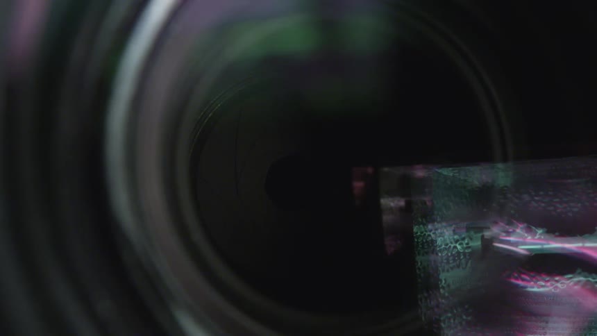 Extreme close up of a camera lens with colorful lights reflecting on it