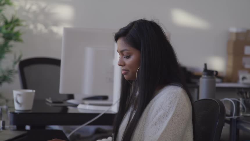 A woman sits at an office computer desk