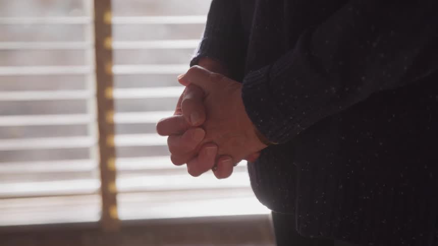 Woman standing in a room with her holding her hands on a prayer