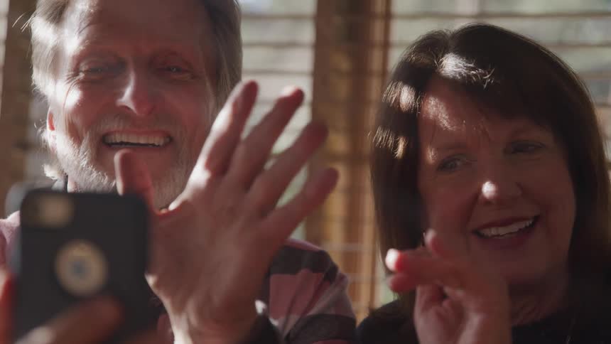 A man and woman wave to their smart phone