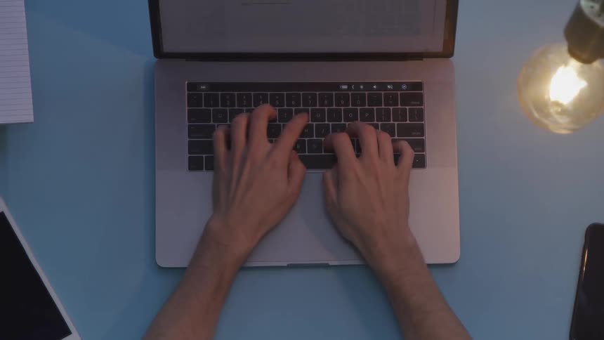 A person turning on a light bulb then typing on a laptop on a table